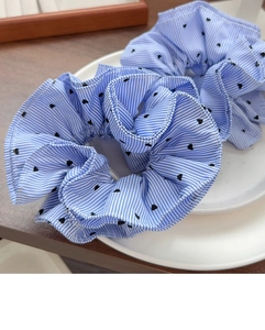 Detail of two blue and white striped scrunchies with heart patterns on a white plate