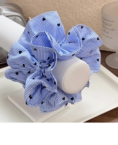 Detail of blue striped scrunchie with heart pattern on a minimalist display stand