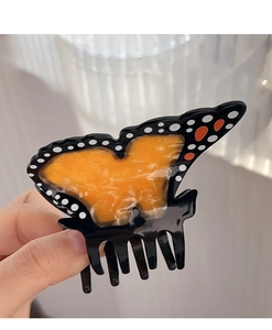 Détail d'une pince à cheveux papillon aux tons ambre avec des motifs d'ailes noirs