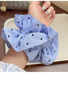 Macro detail of large blue striped scrunchie with heart embroidery on hand