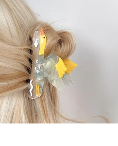Détail d'une pince à cheveux en forme d'oie crème sur cheveux blonds