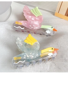 Détail de pinces à cheveux en forme d'oiseau en acétate rose et bleu avec motifs nuages