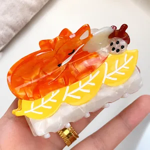 Detailed view of the orange fox and yellow maple leaf acetate hair claw clip accessory