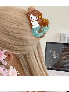 Detail of mermaid hair claw clip with green tail on hair in a lifestyle setting