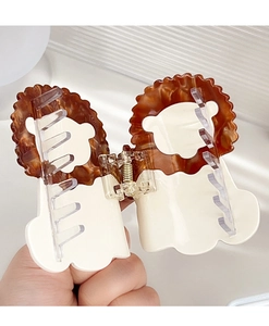 Detail of lion-shaped acetate hair claw clip showing marble pattern and spring mechanism
