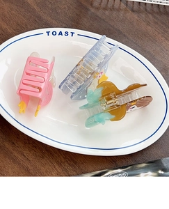 Three-pack mermaid shark hair clips in pink blue and green displayed on a ceramic plate