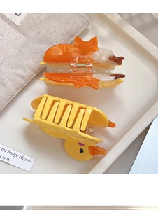 Macro detail of yellow duck and orange fox acetate hair claws on a decorative tray
