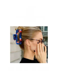 Detail showing a large dark blue acetic acid hair claw with orange floral patterns in hair