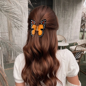 Pince à cheveux papillon orange translucide pour femme dans une coiffure naturelle en plein air
