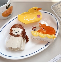 Detailed view of duck lion and fox acetate hair claws on a decorative white ceramic plate