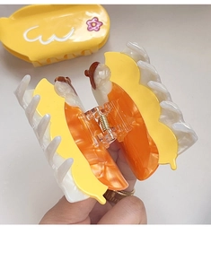 Detailed shot of yellow and orange acetate hair claw clip with floral patterns