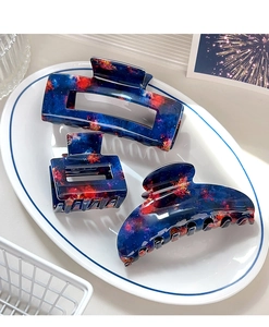 Detailed view of three navy blue acetate hair claws with nebula patterns in a dish