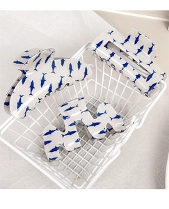 Détail de trois pinces à cheveux blanches avec motifs requins bleus dans un panier