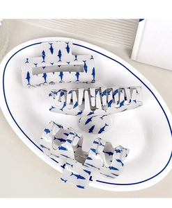 Détail de pinces à cheveux crème avec motifs de requins bleus sur une assiette en céramique