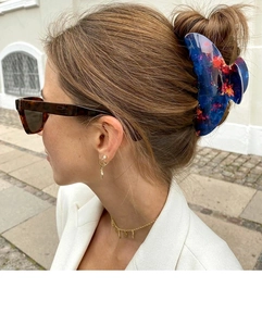 Detail view of large blue firework pattern hair claw clip worn in a high bun hairstyle