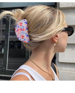 Macro shot of large hair claw clip with star patterns worn by a blonde model