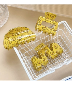 Detail of yellow little duck hair claws in a white wire basket on a beige background