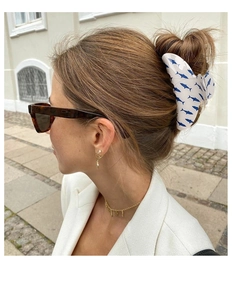 Grande pince à cheveux blanche avec imprimé requin bleu portée par un modèle à l'extérieur