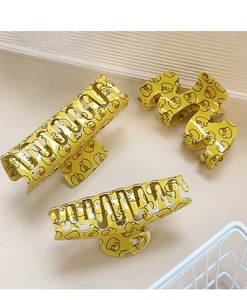 Detailed view of three yellow hair clips with cartoon duck prints and metal springs