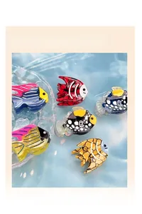 Macro detail of six different acetate fish-shaped hair clips on a blue water background