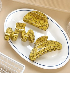 Detailed view of three yellow hair claws with cartoon duck patterns in a ceramic plate