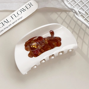 Creamy white acetate hair claw clip with a brown puppy pattern and red bow
