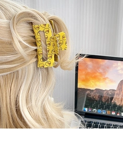 Detail view of a yellow cartoon duck hair claw clip worn on blonde hair in home setting