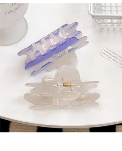 Detail of French hollow cloud hair claws in purple gradient and creamy white acetate texture