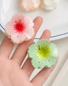 Detail of small translucent cherry blossom hair claw clips in pink and green gradients