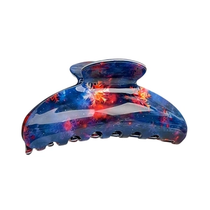 Blue acetic acid hair claw clip with orange starburst patterns on a white background