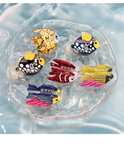 Detailed collection of colorful acetate fish hair claws displayed on a blue water ripple tray