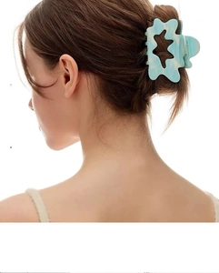 Detail showing a light blue marble texture hair claw with star cutout design
