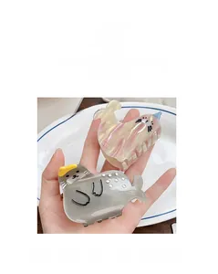 Detail view of gray seal and pink walrus acetate hair claws on a decorative white plate