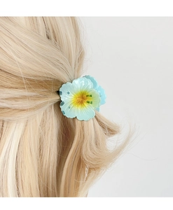 Detailed view of light blue plumeria hair claw clip with yellow gradient flower center