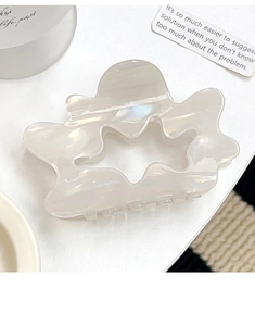 Detailed view of pearlescent white acetate hair claw with hollow star and wavy edges