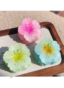 Detailed macro view of resin frangipani hair claws in pink, green, and blue gradient colors