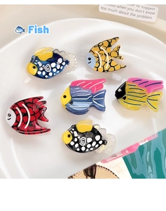 Detailed set of six colorful tropical fish acetate hair clips on a ceramic plate