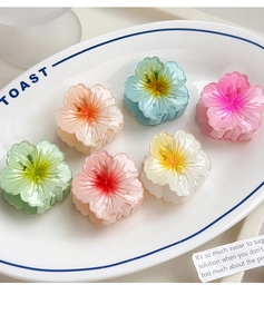 Detailed top view of six colorful resin plumeria flower hair claws in a ceramic bowl