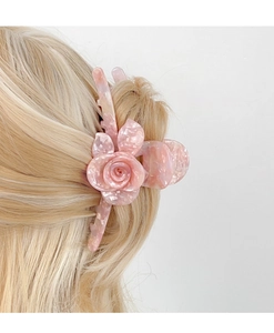 Detail of pink acetate 3D rose flower hair claw clip on blonde hair in a side view