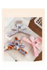 Detailed view of elegant butterfly hair claw clips in pearl pink and amber marble textures