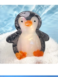 Detailed view of the penguin-shaped hair claw clip with a marble texture and pearlescent belly