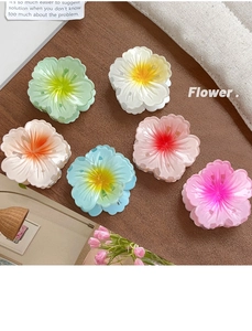 Detailed view of six colorful frangipani hair claws with realistic petal textures