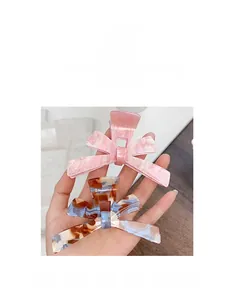 Detail of large acrylic bow hair claw clips in pink glitter and marble texture