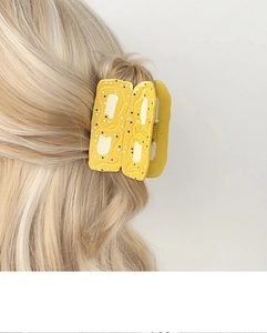 Vue détaillée d'une pince à cheveux en acétate motif toast au beurre sur cheveux