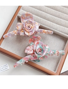 Detailed macro of large 3D acetate flower hair claws with marble texture in display tray