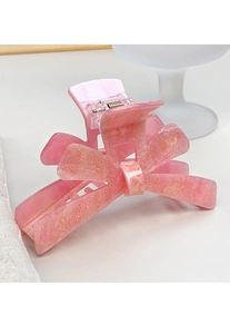 Macro detail of pink bow hair claw clip with golden glitter on acrylic finish