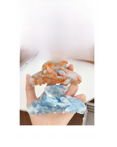 Detail view of acetate tulip hair claw clips with orange and blue marble texture