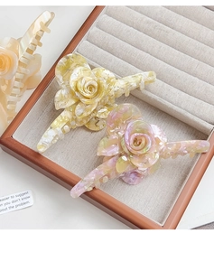 Detailed close-up of marble pattern acetate rose flower hair clips in a jewelry box