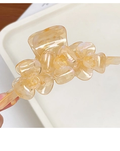 Detail der bernsteinfarbenen Haarklammer mit irisierendem 3D-Rosendesign aus Acetat