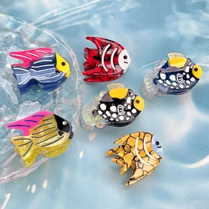 Set of six tropical fish hair clips made of colorful acetate on a blue water ripple surface